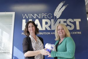 2 ladies posing with a frozen turkey at Winnipeg Harvest
