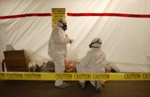 two people in hazmat suits removing asbestos